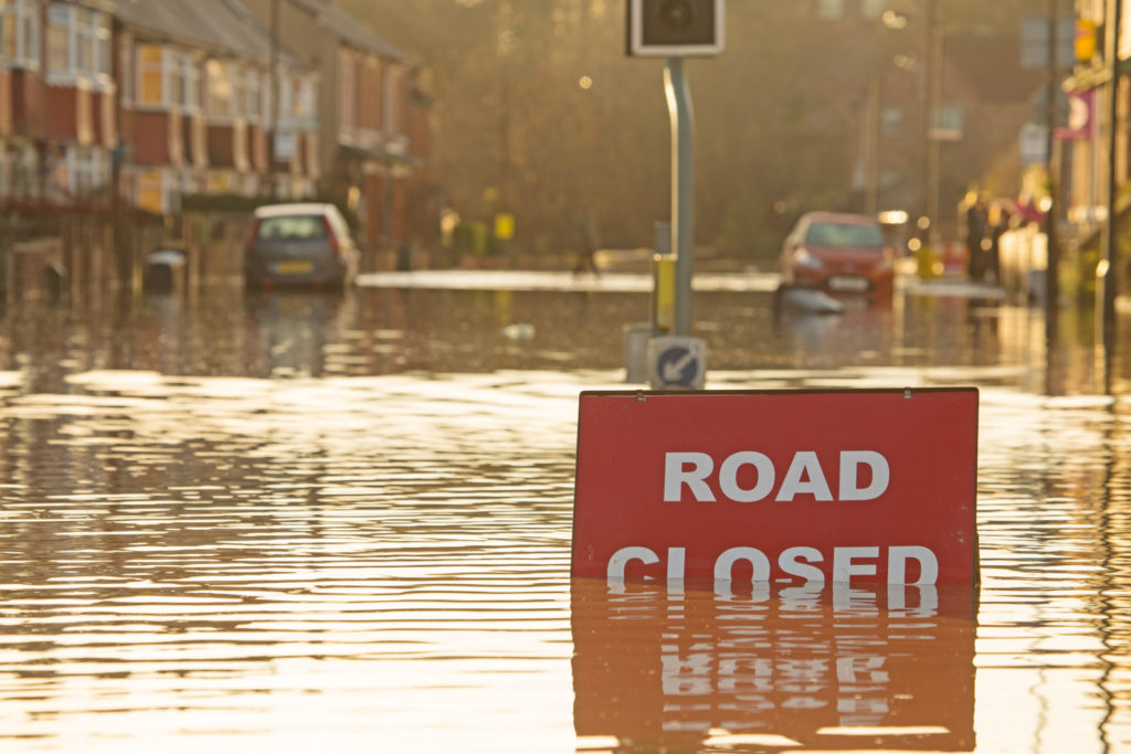 A sign saying Road Closure in a street that is being flooded